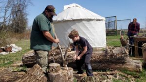 Jarek uses a hatchet to shape a pole. 