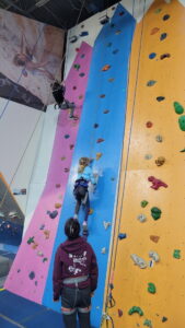 A homeschool rock climbing event. Arya heads up the wall!