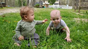 Garrett and Charlie, one of the Home School infants, playing together in the grass. 