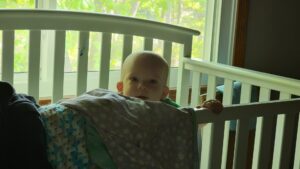 A small Garrett head peeks over the crib rail. Looks like nap time is over!