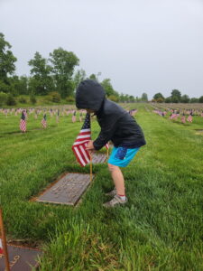 Evan places a flag during the Memorial Day flag placement at the BG William C. Doyle Veterans Memorial Cemetery. This took place Friday of Memorial Day weekend and was a rainy event. 