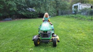 Too big for a lap ride, Arya gets a little experience driving the mower around the yard!