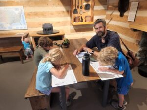 At the Lincoln Birthplace National Monument. The kids were working on their Junior Ranger workbooks and Garrett was getting into mischief in the background. This was a mock up of the cabin with displays of various period implements of life. 