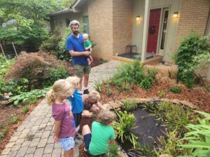 Mrs. Susan shows the kids some plants and other critters living in her garden. 