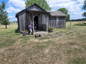 Jarek works the push mower in front of the farm house reconstruction. 