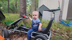 Garrett at the neighbors inspecting the go kart. He's a fan of all things with a steering wheel. 